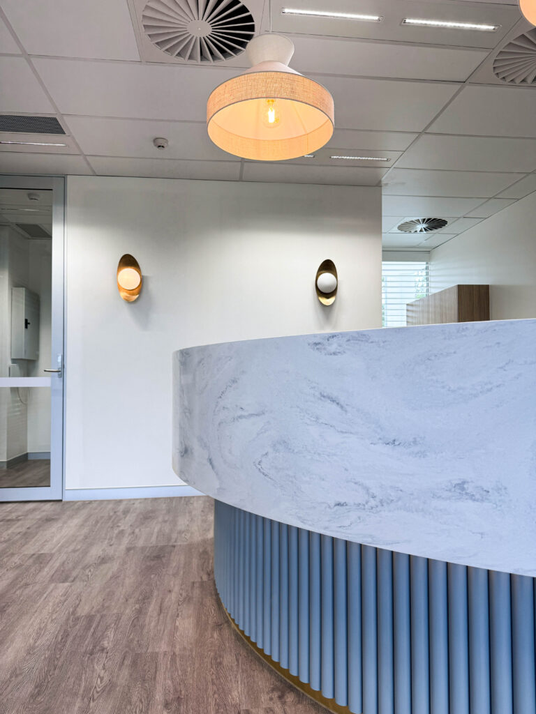 Curved reception counter with pendant lighting and wall sconces in a modern medical practice interior