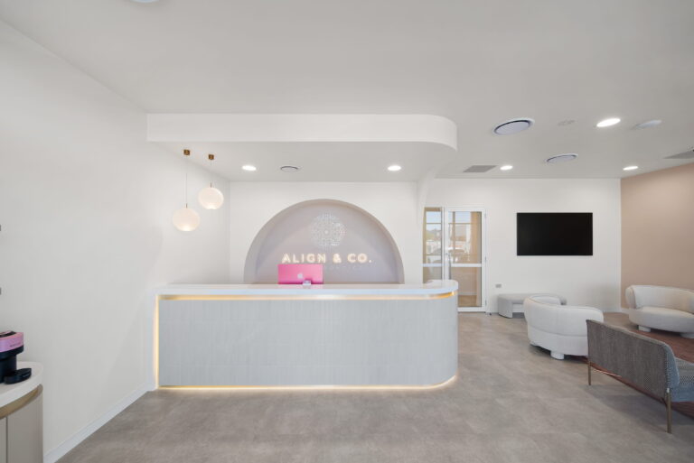Curved reception desk with feature arch wall and illuminated signage at Align & Co. Orthodontics clinic fitout in Pimpama QLD