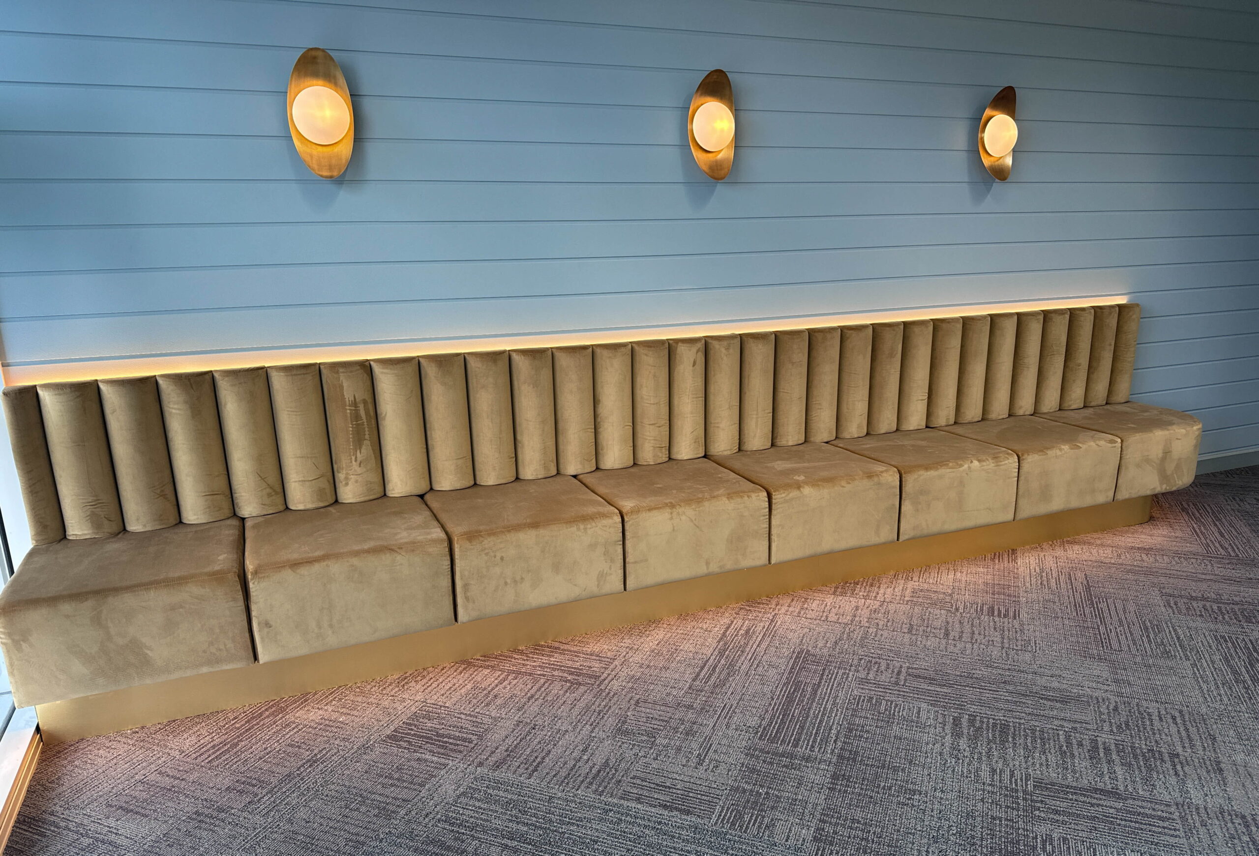 Upholstered bench seating along a feature wall with decorative lighting in a modern clinic waiting area