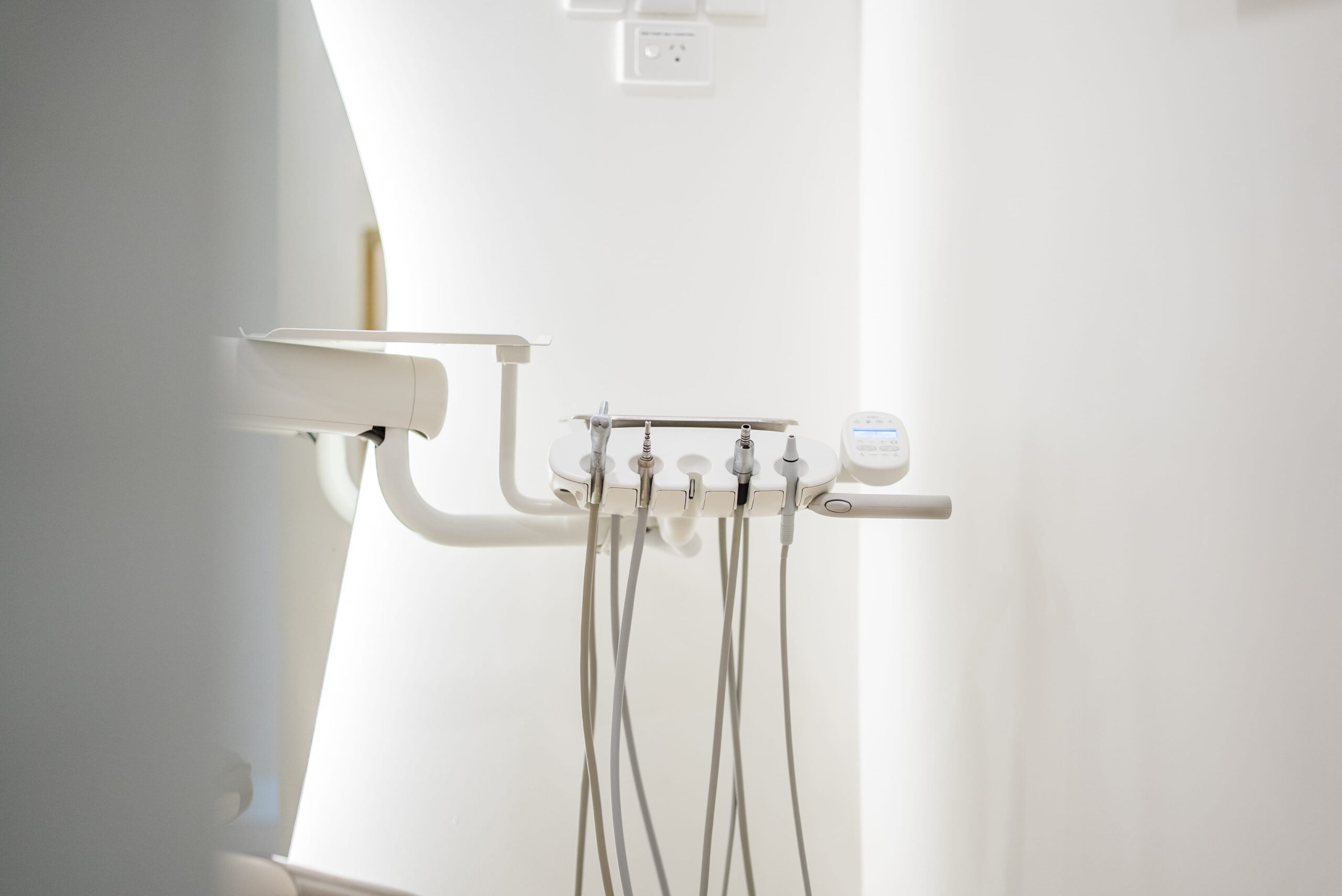 Dental treatment room with mounted clinical equipment, clean white finishes and a minimalist patient-focused design