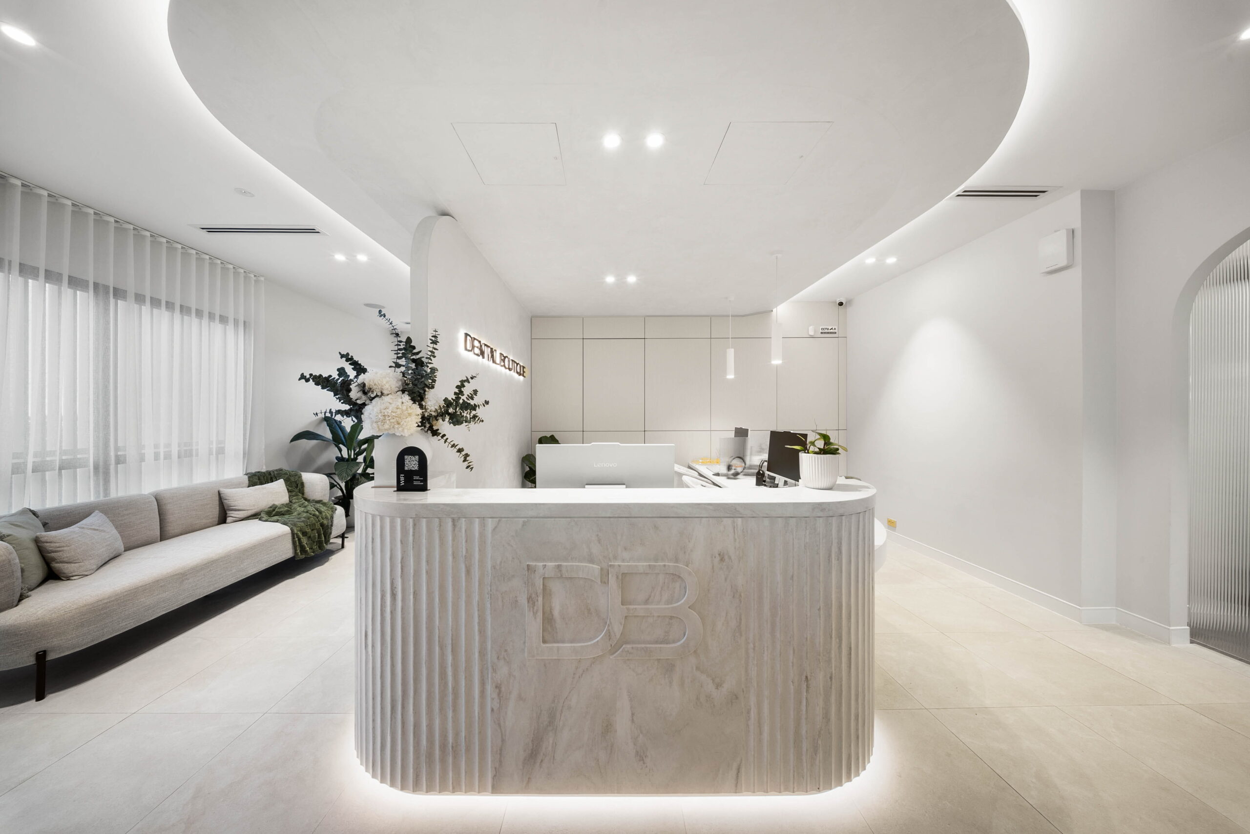 Luxury clinic reception featuring a curved stone reception desk, soft lighting and a spacious waiting area