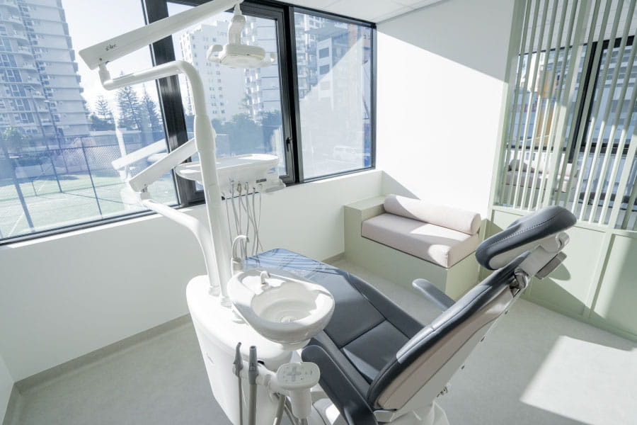 Bright dental treatment room with a patient chair, large windows and integrated dental equipment