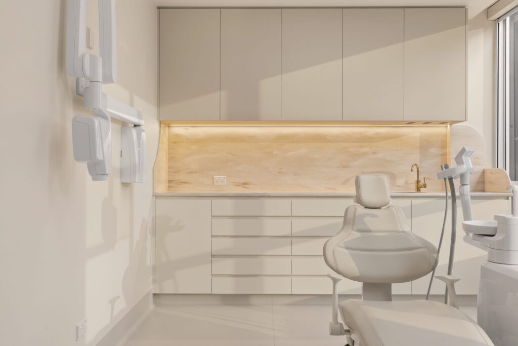 Modern dental treatment room with custom cabinetry, imaging equipment and a patient chair