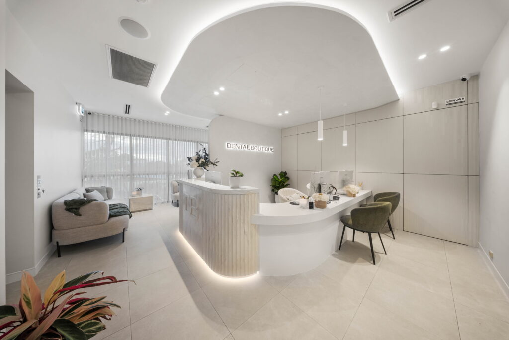 Contemporary dental reception with curved ceiling feature, concealed lighting and illuminated reception desk.