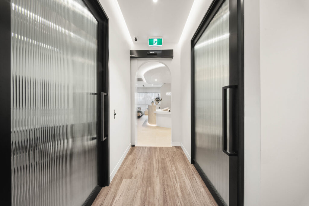Dental clinic corridor with concealed ceiling lighting leading towards a softly lit reception area