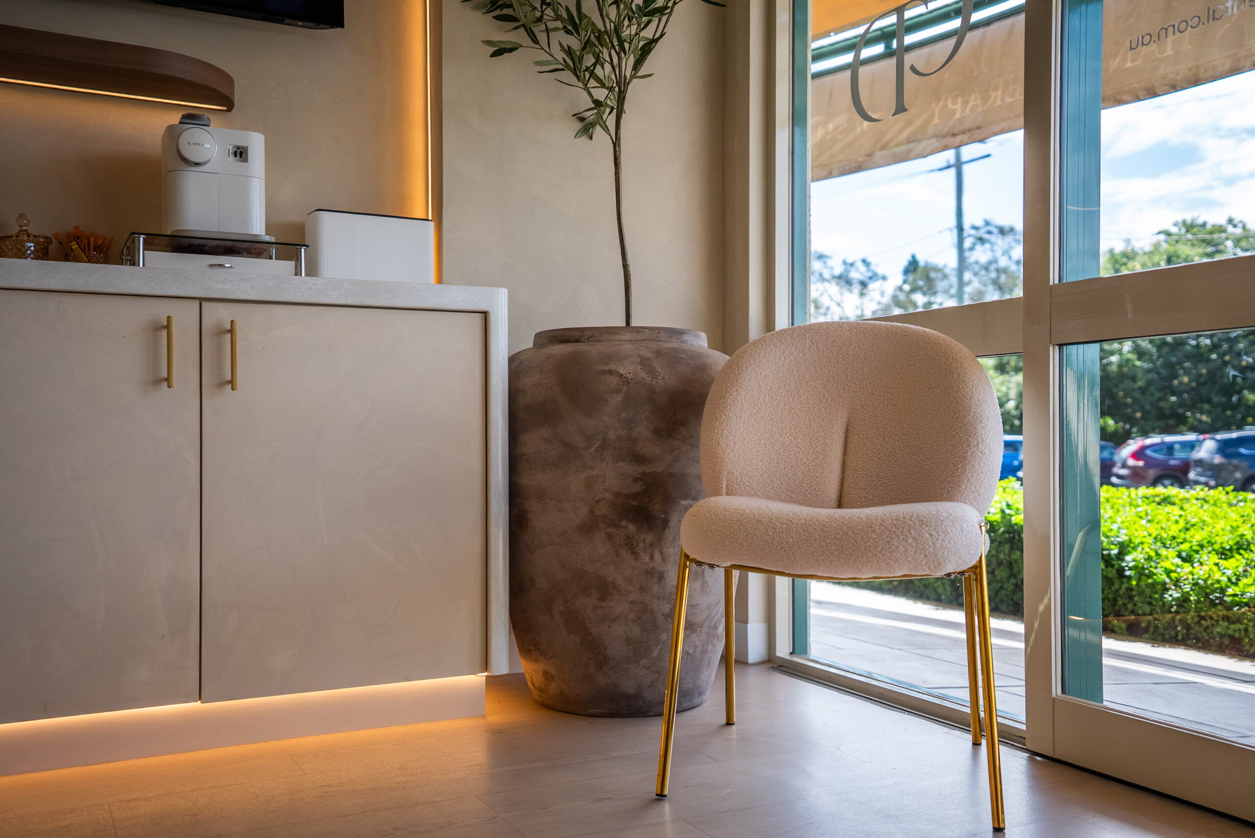 Close-up of patient seating beside reception cabinetry and a large window in a contemporary dental clinic