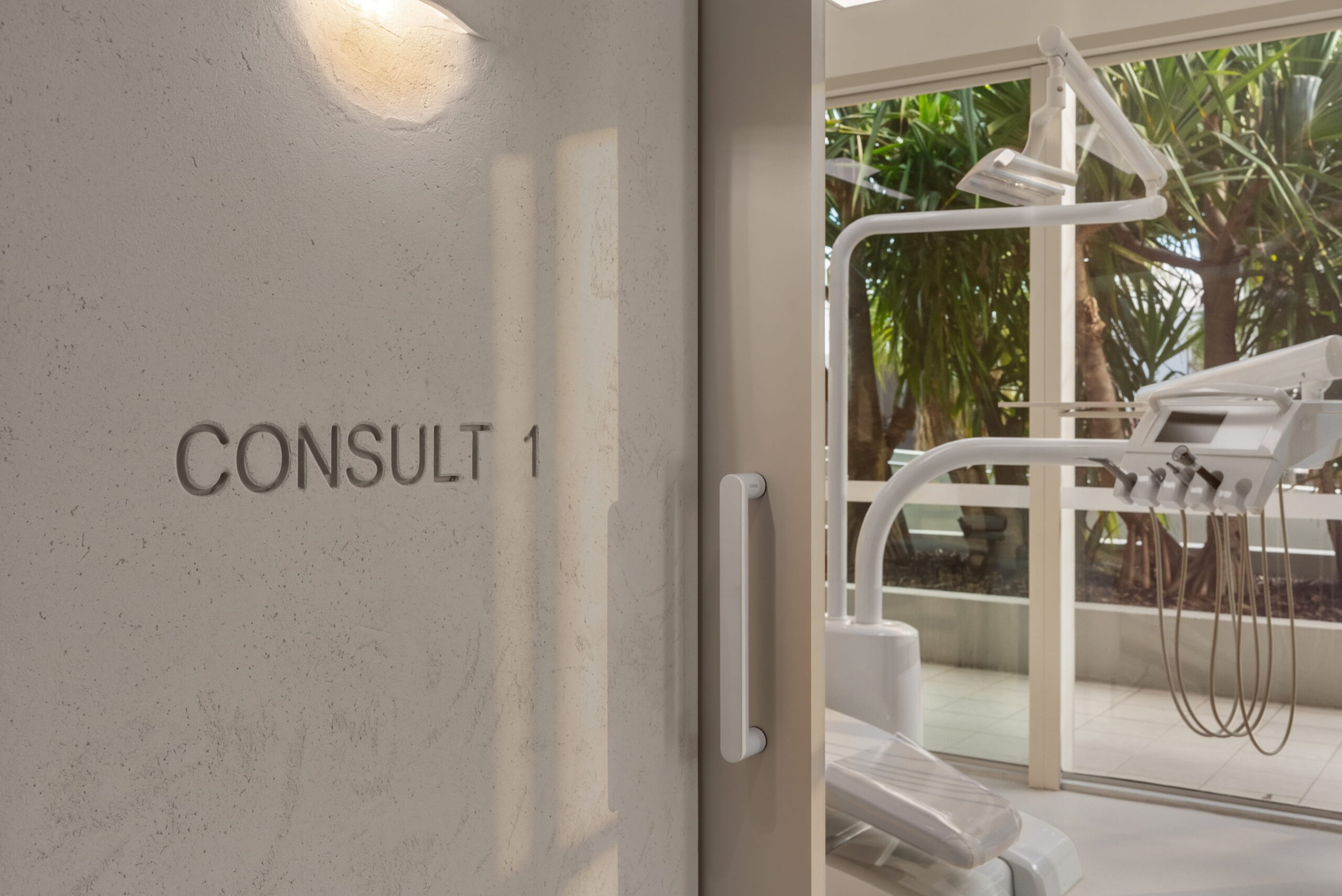 Dental treatment room entrance showing a patient chair and dental equipment beside a large window