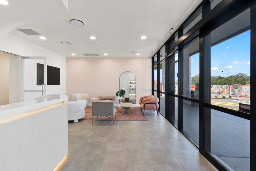 Reception and waiting area with curved desk, soft seating and floor-to-ceiling windows at Align and Co. Orthodontics